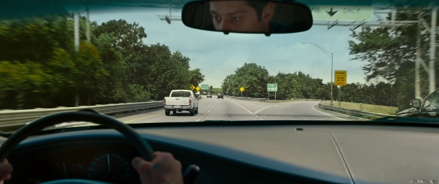 Wide shot frame from The King of Staten Island — street, car, hand