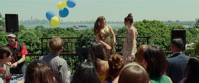 Wide shot frame from The King of Staten Island — sitting, standing, table