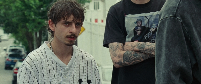 Wide shot frame from The King of Staten Island — standing, street, shirt
