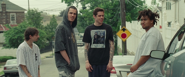 Wide shot frame from The King of Staten Island — standing, street, car