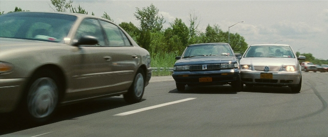 Wide shot frame from The King of Staten Island — street, car, wheel
