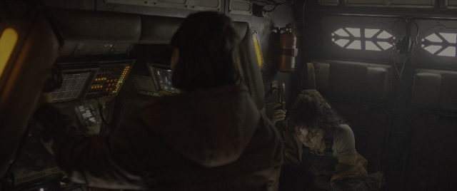 Wide shot frame from Alien: Romulus — sitting, room, gun