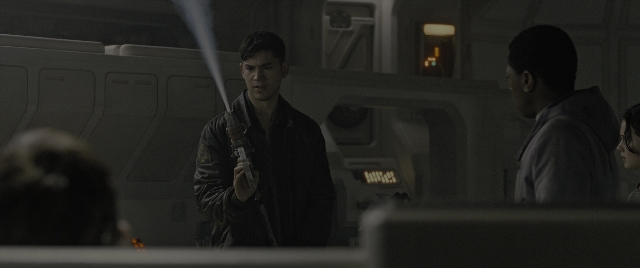 Wide shot frame from Alien: Romulus — standing, room, hand