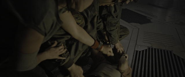 Wide shot frame from Alien: Romulus — sitting, hand, train