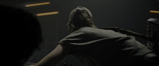 Wide shot frame from Alien: Romulus — sitting, room, shirt
