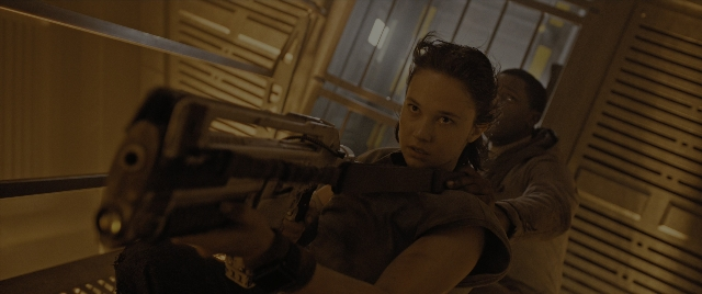 Wide shot frame from Alien: Romulus — standing, room, gun