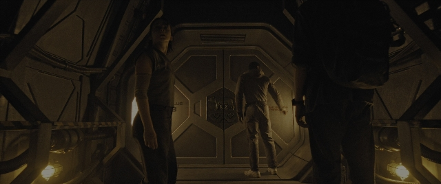 Wide shot frame from Alien: Romulus — standing, room, door