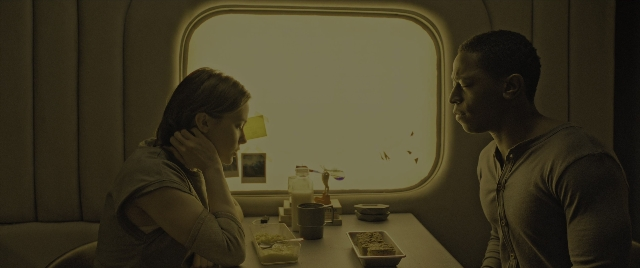 Wide shot frame from Alien: Romulus — sitting, table, hand