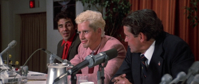 Wide shot frame from The Adventures of Buckaroo Banzai Across the 8th Dimension — sitting, room, table