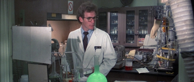 Medium shot frame from The Adventures of Buckaroo Banzai Across the 8th Dimension — standing, table, coat
