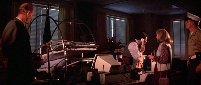 Wide shot frame from The Adventures of Buckaroo Banzai Across the 8th Dimension — standing, room, bed