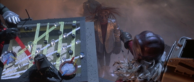 Wide shot frame from The Adventures of Buckaroo Banzai Across the 8th Dimension — standing, hat, hand