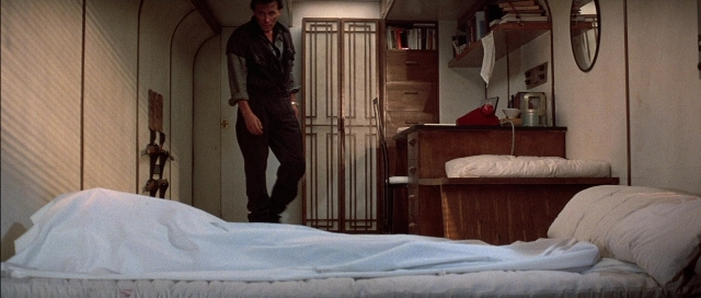 Wide shot frame from The Adventures of Buckaroo Banzai Across the 8th Dimension — standing, room, bed