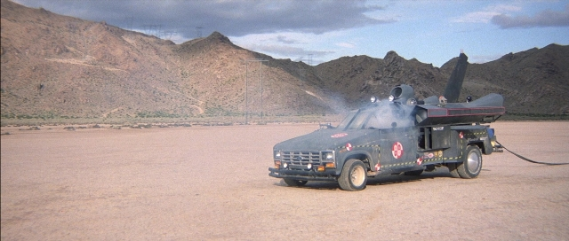 Frame from The Adventures of Buckaroo Banzai Across the 8th Dimension — car, truck, smoke