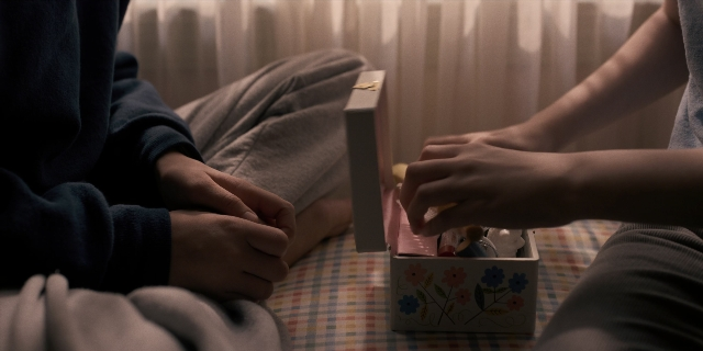 Wide shot frame from Stranger Things — sitting, bed, box