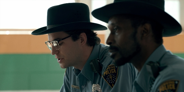 Medium shot frame from Stranger Things — standing, room, hat