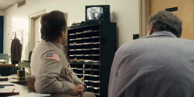 Wide shot frame from Stranger Things — sitting, room, flag