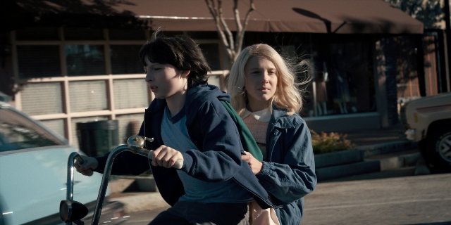 Wide shot frame from Stranger Things — standing, street, car