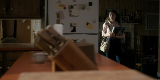 Wide shot frame from Stranger Things — book, standing, table