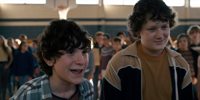 Wide shot frame from Stranger Things — standing, dialogue, shirt