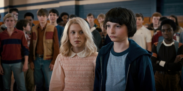 Wide shot frame from Stranger Things — sitting, standing, hair