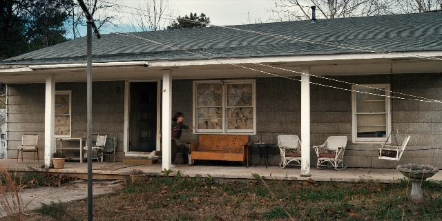 Wide shot frame from Stranger Things — standing, table, house