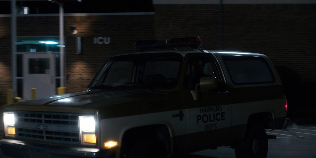 Wide shot frame from Stranger Things — plate, street, car