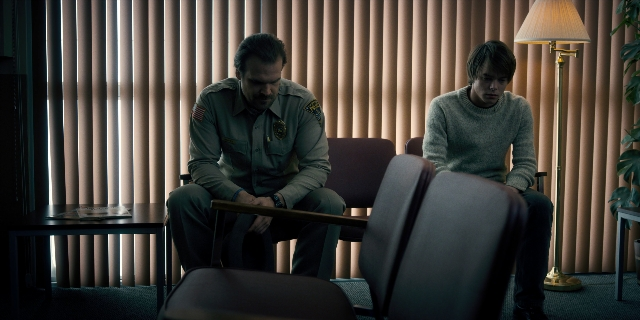 Wide shot frame from Stranger Things — sitting, room, table