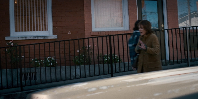 Wide shot frame from Stranger Things — standing, phone, door