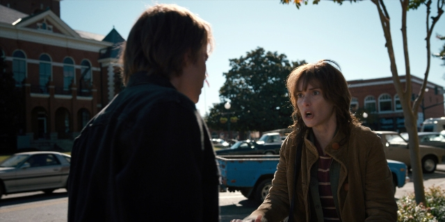 Wide shot frame from Stranger Things — standing, street, car