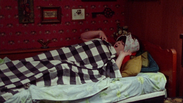 Wide shot frame from Female Trouble — bed, hat, shirt