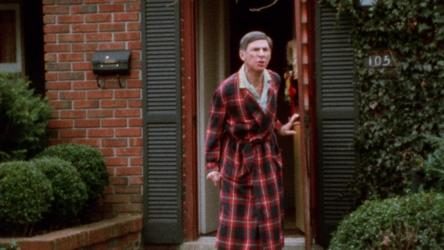 Wide shot frame from Female Trouble — standing, door, hand
