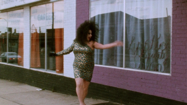 Wide shot frame from Female Trouble — walking, street, car