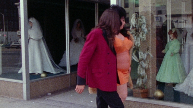 Wide shot frame from Female Trouble — walking, dialogue, street
