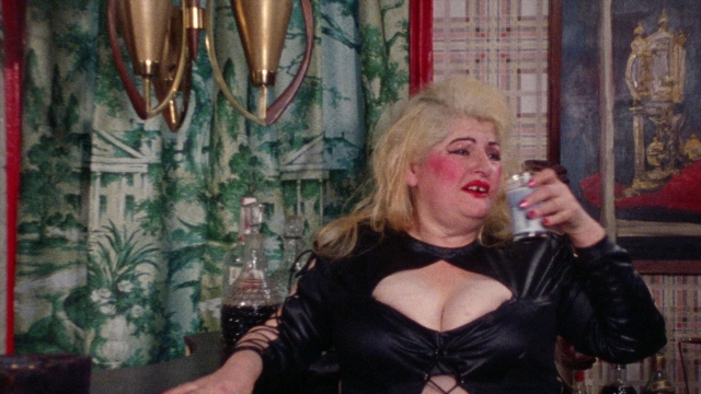 Wide shot frame from Female Trouble — sitting, room, dialogue