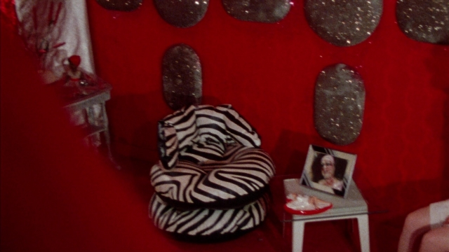 Wide shot frame from Female Trouble — plate, room, table