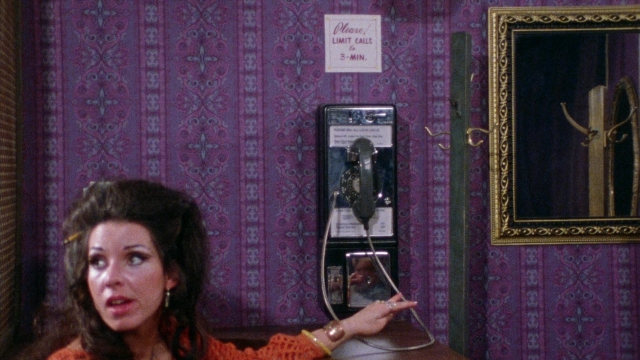 Wide shot frame from Female Trouble — sitting, room, dialogue