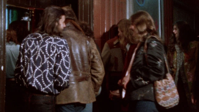 Wide shot frame from Female Trouble — standing, room, dialogue