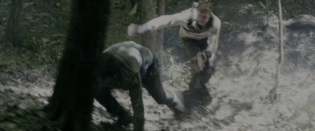 Wide shot frame from The Maze Runner — standing, hand, gun