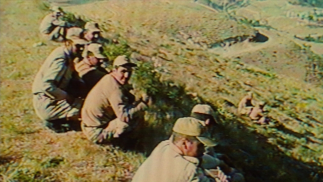 Wide shot frame from Ta'm e guilass — sitting, dialogue, gun