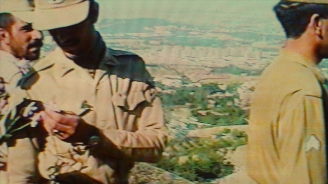 Wide shot frame from Ta'm e guilass — standing, dialogue, hat