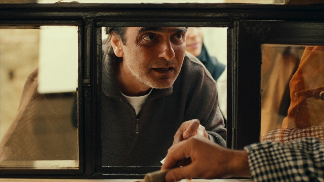 Wide shot frame from Ta'm e guilass — sitting, room, table