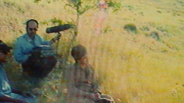 Wide shot frame from Ta'm e guilass — sitting, dialogue, street