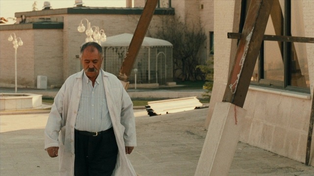 Wide shot frame from Ta'm e guilass — walking, street, coat