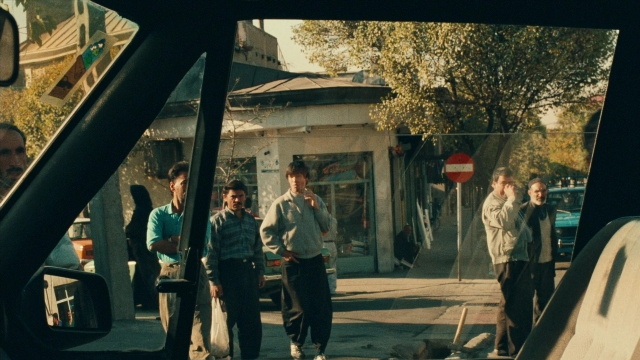 Close-up frame from Ta'm e guilass — standing, walking, street