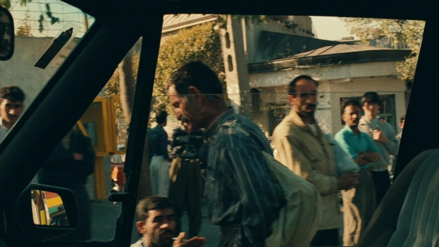 Wide shot frame from Ta'm e guilass — sitting, standing, dialogue