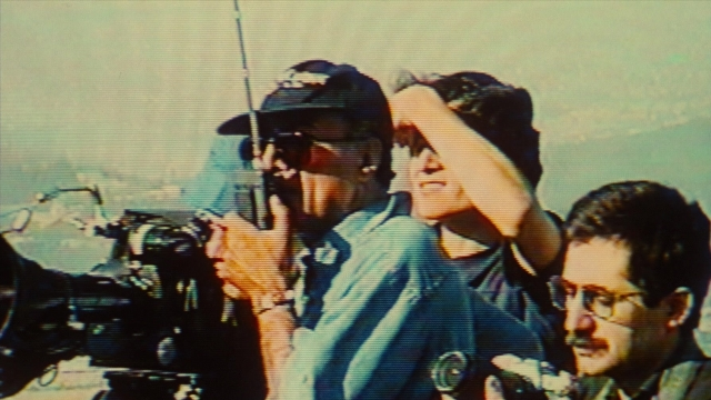 Wide shot frame from Ta'm e guilass — standing, hat, hand