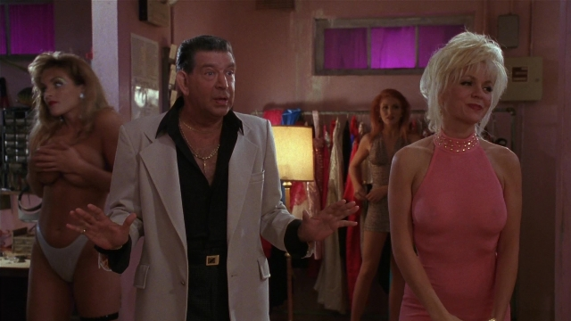 Wide shot frame from Striptease — standing, room, suit