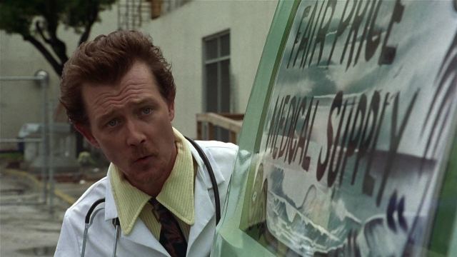 Wide shot frame from Striptease — standing, coat, face