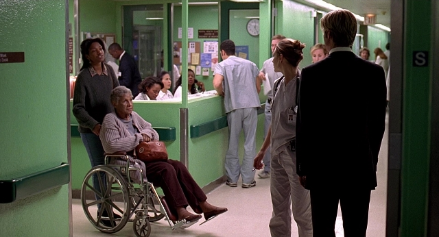 Wide shot frame from Meet Joe Black — standing, suit, clock